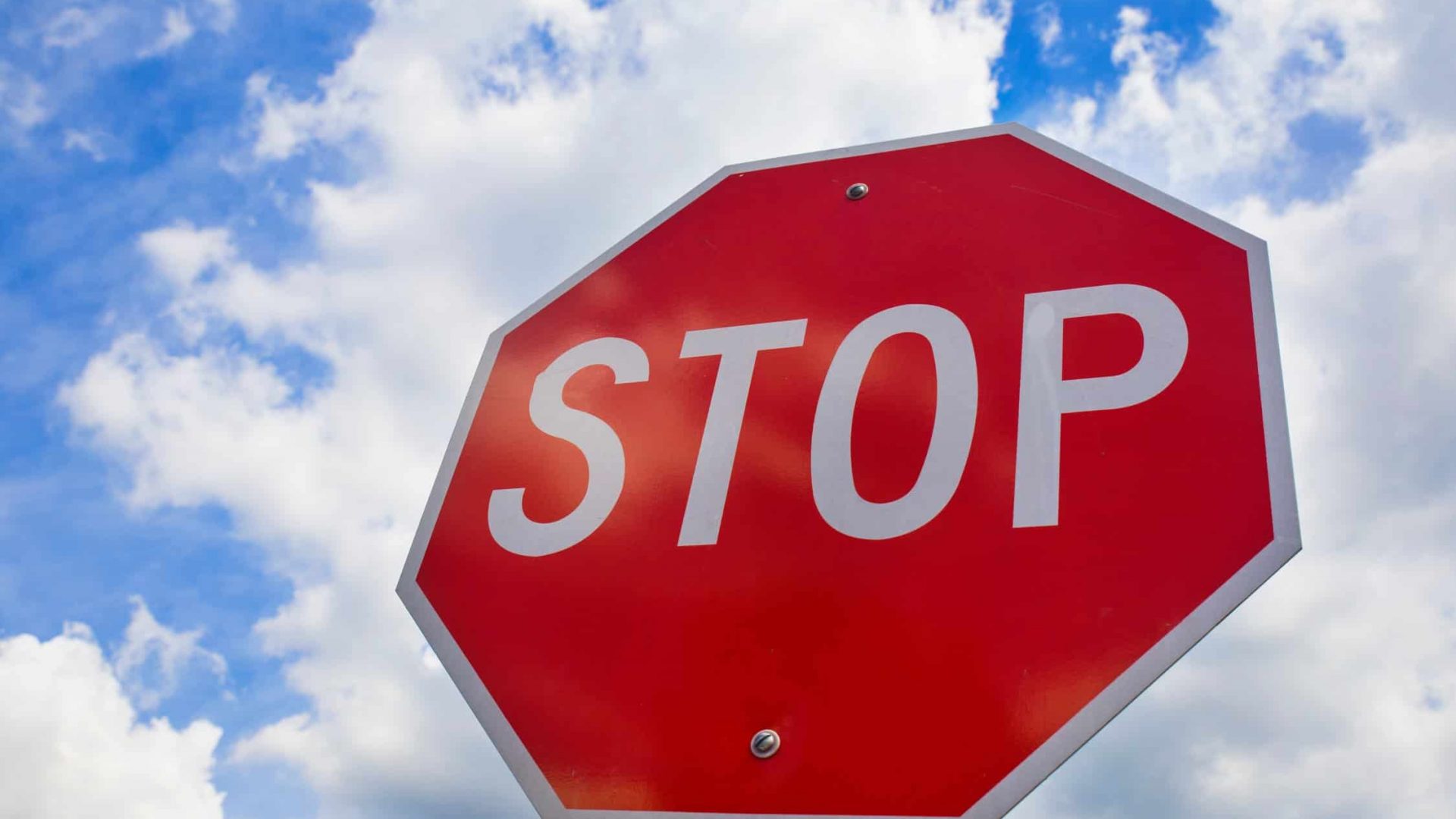 Red stop sign on the street, roadside traffic sign for stopping.